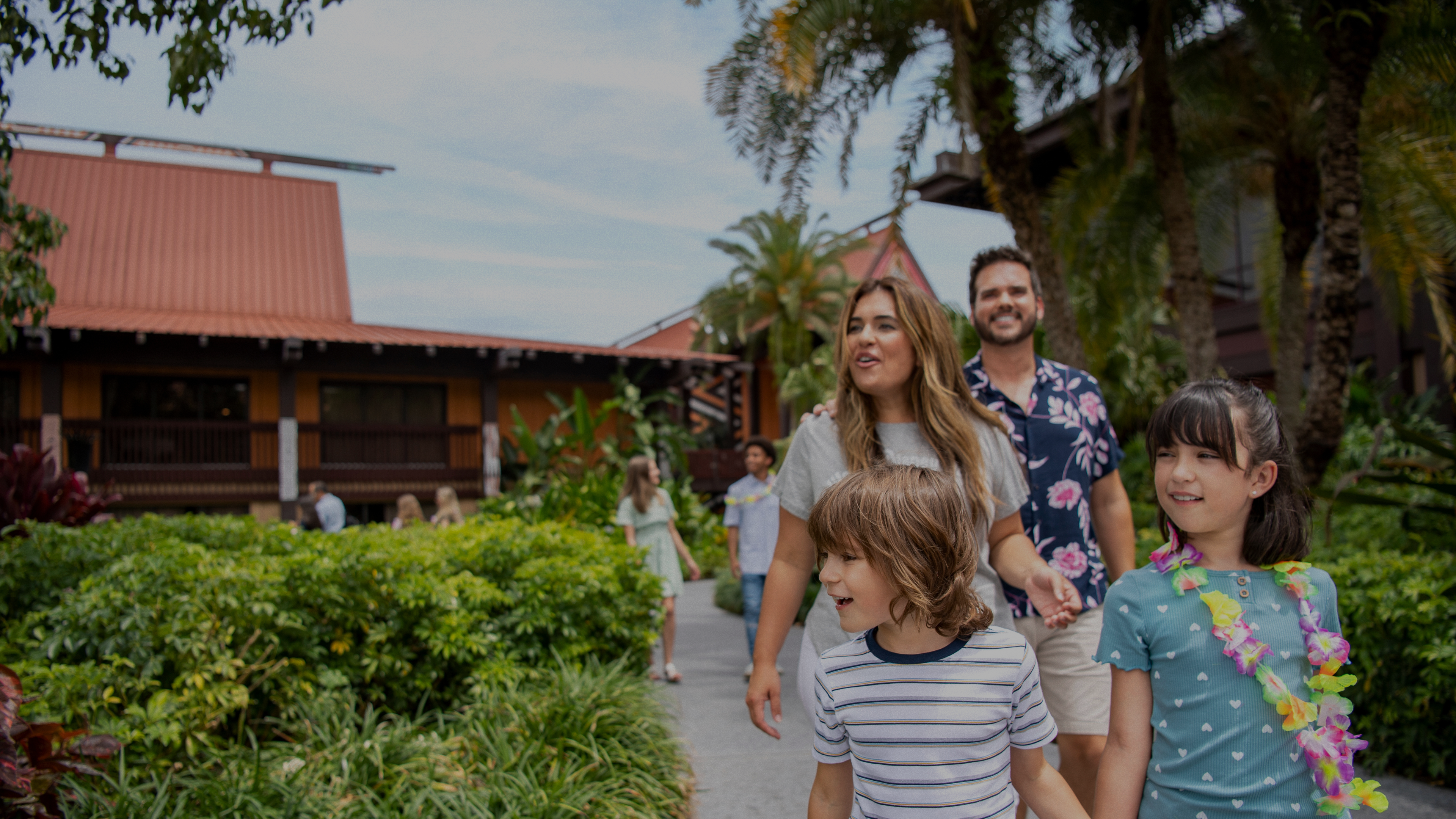An image of a happy family enjoying their time at Disney World's Polynesian Resort. The family is seen smiling and relaxing in a lush tropical setting, surrounded by palm trees and beautiful landscaping. They are wearing casual vacation attire and appear to be enjoying the resort's amenities and the magical atmosphere of the Disney experience.